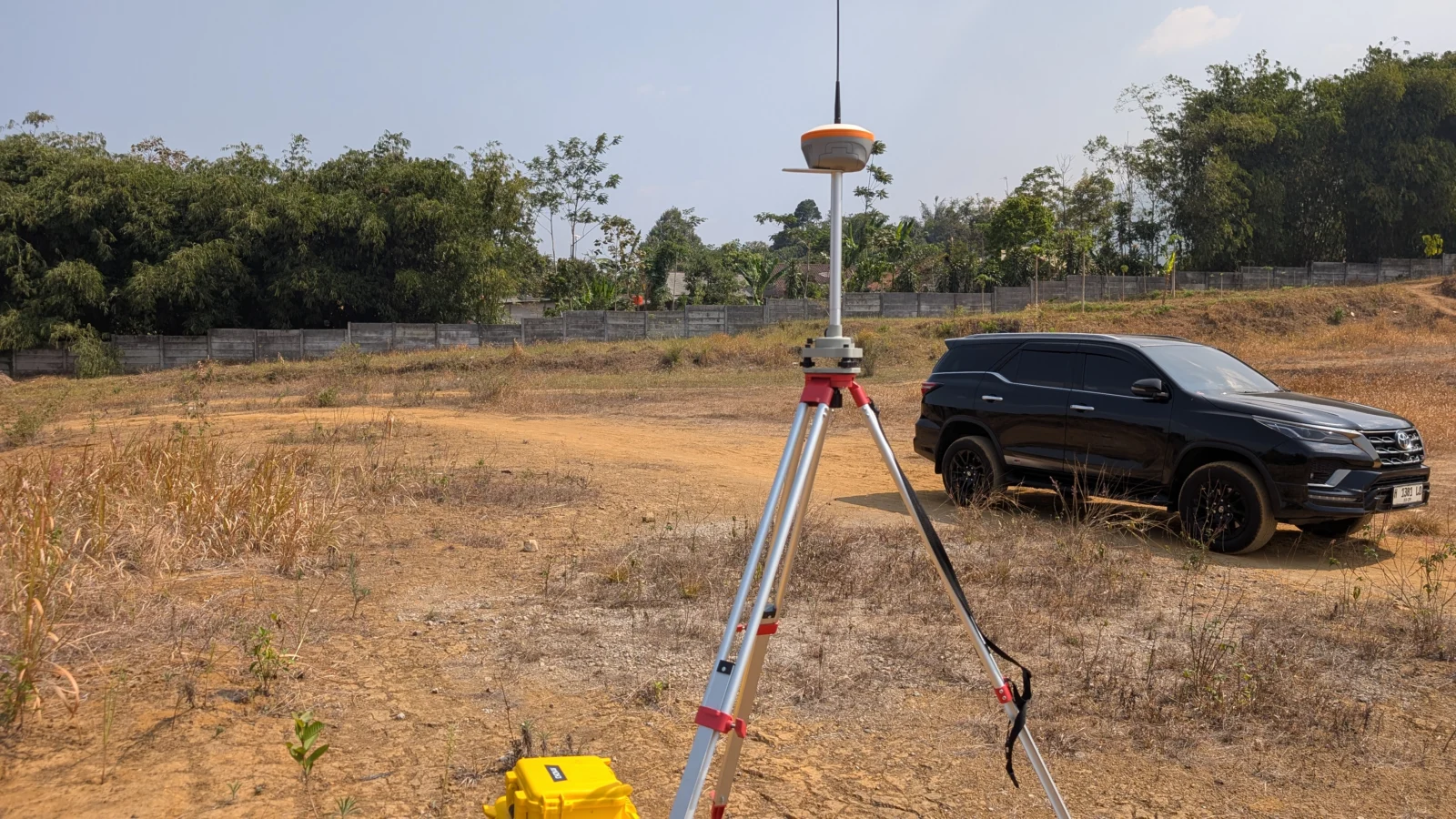 Receiver GNSS RTK terpasang di atas tripod di lahan terbuka