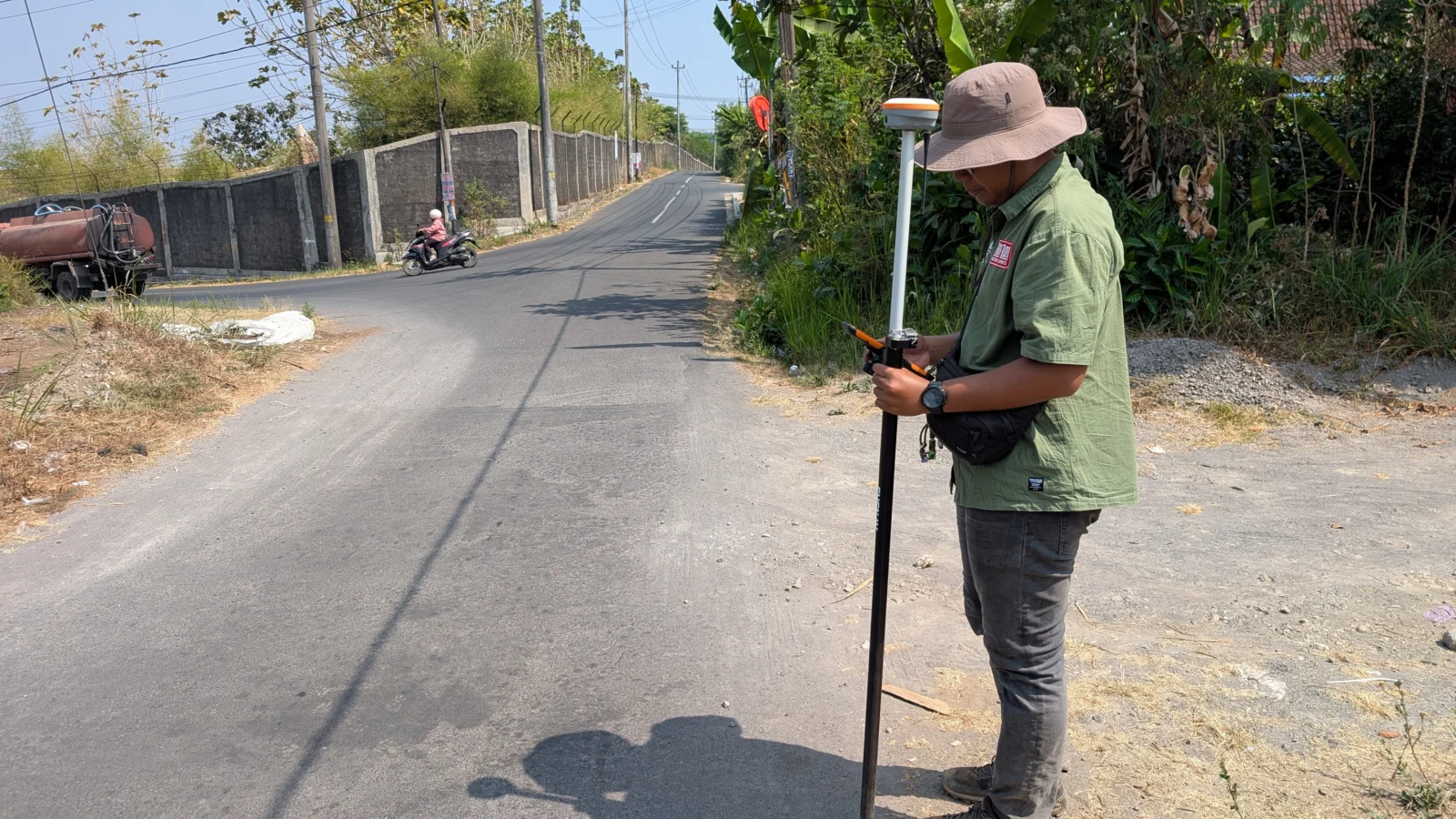 Surveyor mengukur titik dengan GNSS RTK rover di tepi jalan