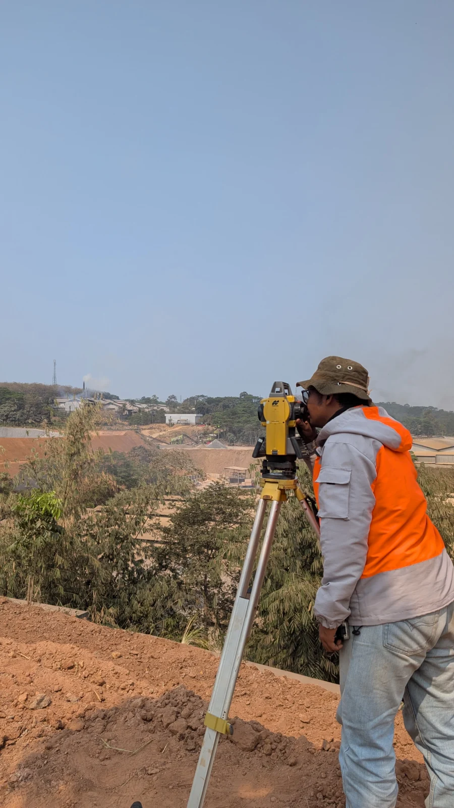 Surveyor mengoperasikan total station di area lereng