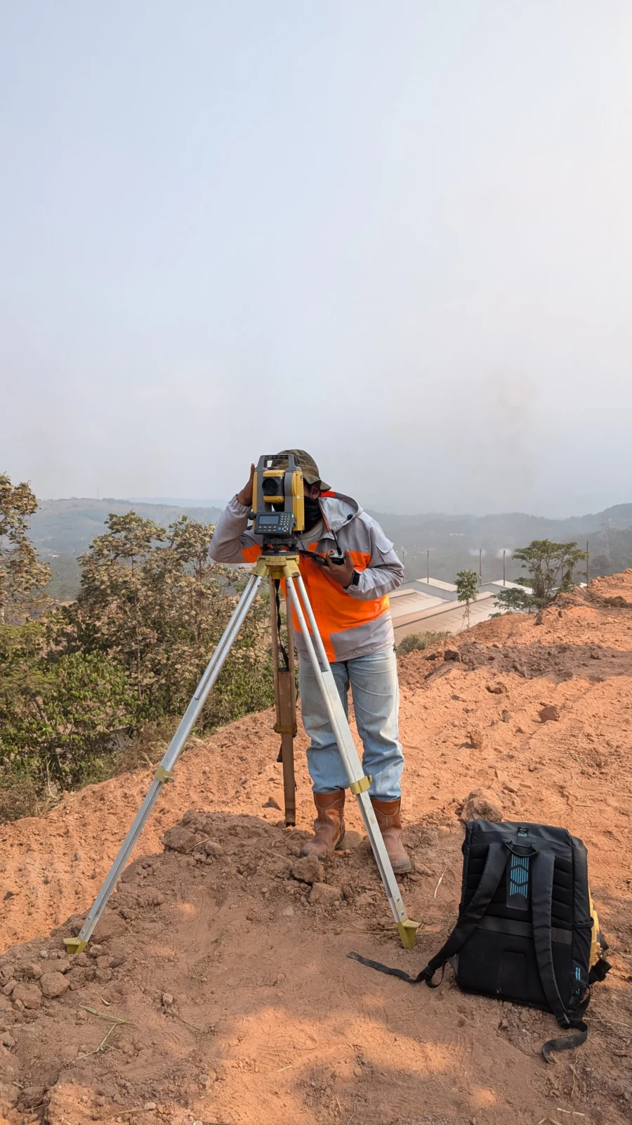 Total station di atas tripod di area bukit proyek